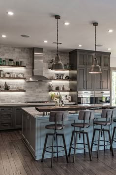 a kitchen with gray cabinets and bar stools in the center, along with wooden flooring