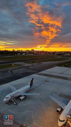 an airplane is parked on the tarmac at sunset with clouds in the sky behind it