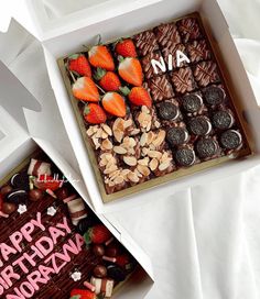 two boxes filled with different types of chocolates and strawberries next to each other