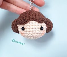 a crocheted doll keychain is being held by a hand