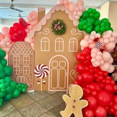 a gingerbread house is decorated with balloons and candy canes for the holiday season