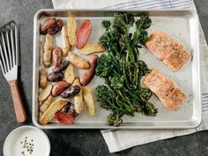 a tray with broccoli, potatoes and salmon on it next to a fork