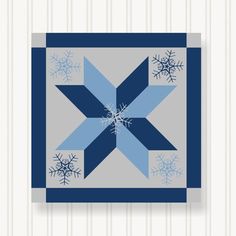 a blue and gray quilt with snowflakes on it's center, as well as an x in the middle