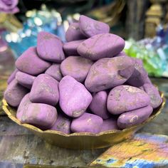 a bowl filled with purple rocks sitting on top of a table