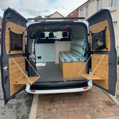 the back end of an empty van with its doors open and mattresses in place