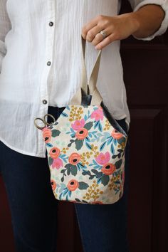 a woman is holding a purse with flowers on it and the handles are open to show