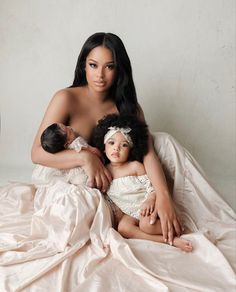 a woman holding a baby on top of a bed