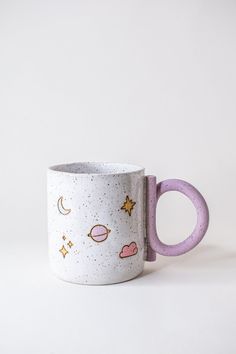 a white and purple coffee mug with stars, planets, and clouds on the inside