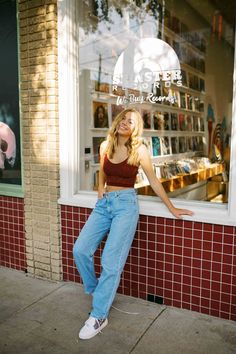 a woman leaning up against a window in front of a store