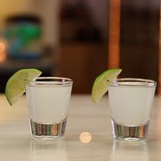 two shot glasses with lime wedges on the rim