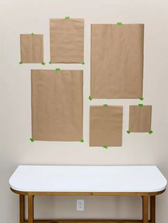 several pieces of brown paper taped to the wall above a white table with green tape on it