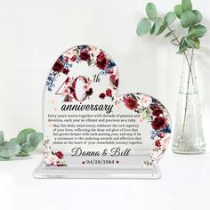 an anniversary plaque with flowers on it next to a vase