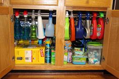 an organized kitchen cabinet filled with cleaning products