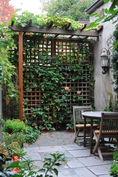 an outdoor dining area with table and chairs, surrounded by greenery on the walls