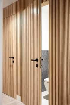 an open bathroom door with wooden slats on the wall and toilet in the background