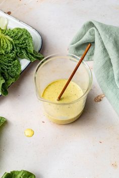 lettuce and dressing in a small glass container with a wooden spoon next to it