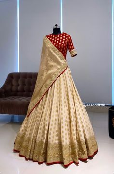 a white and red silk saree with gold dots on the border, in front of a brown couch