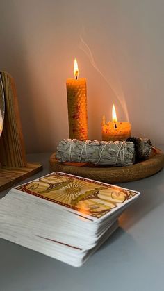 three lit candles sitting on top of a table next to a card holder and coaster