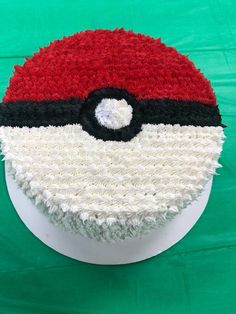 a pokemon poke ball cake is on a white plate with green cloth in the background