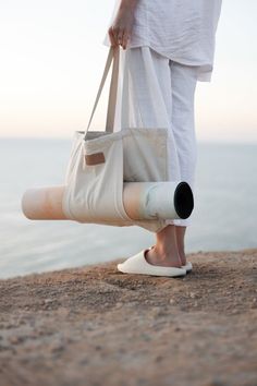 a person standing on top of a beach holding a white bag