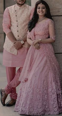 two people standing next to each other wearing pink outfits and posing for the camera with their arms around each other