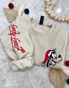 Join the festive fun this holiday season with Mr. Goofster! Wrap yourself in cozy comfort in our soft blended sweater, featuring a jolly Mr. Goofster in a Christmas hat embroidered on the chest, and his whimsical autograph along the right sleeve. It's the perfect way to spread holiday cheer with your favorite pal! ✦Sweater design features two embroidered locations. ✦Choose your preferred colored crew! ✦Interested in a different character? Head over to our "All Crewnecks" tab or type 'Christmas Autograph Crewneck' in the search bar to see the other characters! ✦Want to pair this sweater with our mouse ears? Browse our ear selection to find your favorite match! Holiday Embroidered Casual Sweatshirt, Casual Embroidered Holiday Sweatshirt, Casual Holiday Embroidered Sweatshirt, Casual Embroidered Sweatshirt For Holiday, Casual Christmas Sweater With Embroidery, Winter Embroidered Sweater For Loungewear, Casual Christmas Sweater For Loungewear, Character Head, Christmas Hat