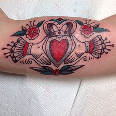 a tattoo on the arm of a woman with an anchor and heart surrounded by flowers