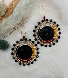 two pairs of black and red beaded earrings with gold accents on white furnishing