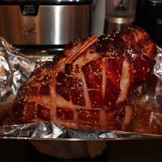 a cooked ham in foil sitting on top of a stove