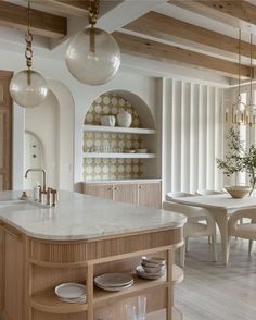 a kitchen with an island and marble counter tops in the center, surrounded by white chairs