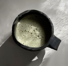 a black cup filled with liquid on top of a white table