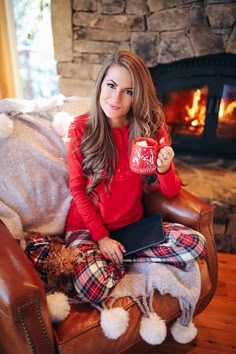 a woman sitting in a chair holding a coffee mug and teddy bear while looking at the camera