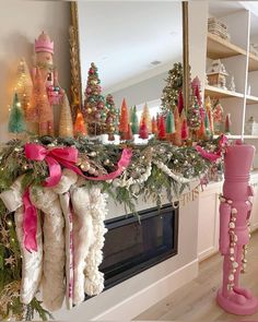 a fireplace mantel decorated with christmas stockings and pink bows, candles and other holiday decorations