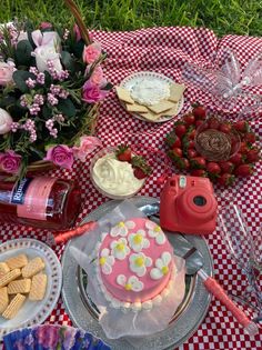 a table topped with plates and cakes covered in frosting next to flowers, strawberries and crackers