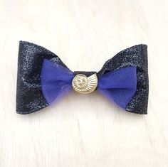 This handmade bow is made with sparkly black fabric ribbon and a purple tulle accent bow. It's all topped off with a glitter painted Ursula the Sea Witch's nautilus shell (Ariel's voice not included) * Comfortable and light weight * Made from durable fabric material * Great for kids and adults! - Size  4 1/2 inches (11  1/2 cm) Long   1  1/2 inches (6 cm) Tall Hair Clip Bow, Purple Tulle, Gardening Hat, Minnie Mouse Bow, Scary Costumes, Nautilus Shell, Glitter Paint, Disney Ears, Ear Candy