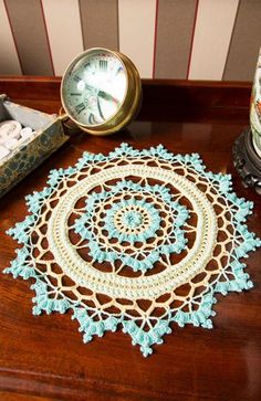 there is a doily on the table next to two candles and an alarm clock