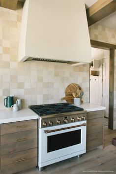 a stove top oven sitting inside of a kitchen next to a wall mounted range hood