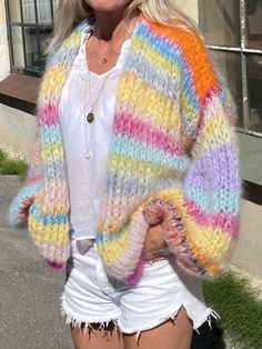 a woman in white shorts and a colorful cardigan sweater is posing for the camera