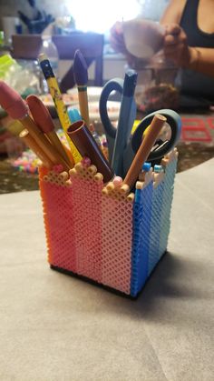 a cup filled with lots of different colored pencils and pens on top of a table