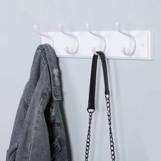 a pair of jeans hanging on a coat rack next to a denim jacket and chain