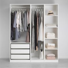 a white closet with clothes hanging on the shelves and other items in front of it