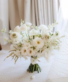 a bouquet of white flowers sitting on top of a table in front of a window