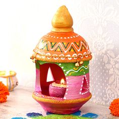 a colorful candle holder sitting on top of a table next to orange pom poms