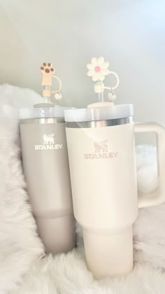 two travel mugs sitting next to each other on a fluffy white blanket with flowers