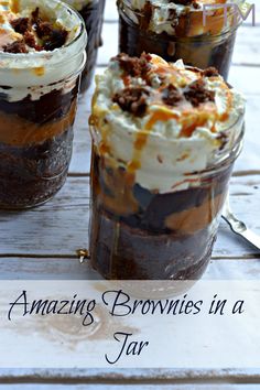 three jars filled with desserts sitting on top of a white wooden table and the words amazing brownies in a jar