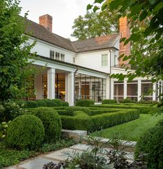 a large white house sitting next to a lush green garden