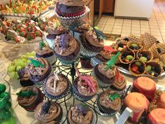 a table topped with lots of cupcakes covered in frosting and toppings