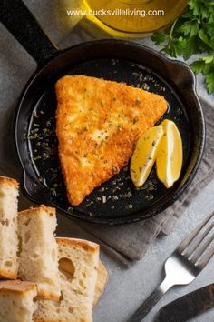 two slices of pizza sitting on top of a pan next to bread and lemon wedges