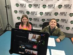 two young children sitting at a table with a laptop computer in front of them on display