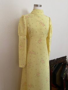 DESCRIPTION*60s Long Sleeve Maxi Dress in pale yellow *A mixture of Daisy foliage and polka dot flowers*Lightweight, slightly textured Polyester material *High Mandarin Collar with Puffy Sleeves and an empire Waistline*Belt that frames the empire waistline and ties in the back*Fitted silhouette with slight flair in the skirt*Pleating on the Bust*Zipper Closure from top to bottom*Perfect for a wedding or a 60s costume!DETAILS*Label: Handmade*Size: Small to Medium, see measurements below*Color: Pa Vintage Yellow Dress, 60s Costume, Dot Flowers, Yellow Vintage Dress, Yellow Long Dress, 70s Bohemian, Yellow Cottage, Costume Inspo, Empire Waistline